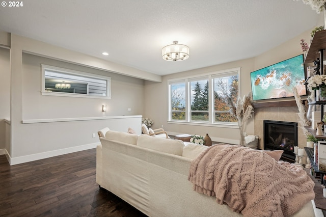 living room featuring dark hardwood / wood-style flooring, a tile fireplace, and a chandelier