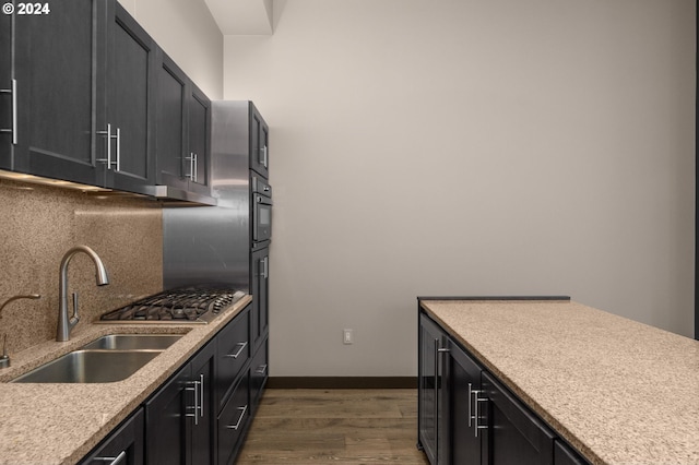 kitchen with decorative backsplash, stainless steel oven, dark hardwood / wood-style flooring, and sink