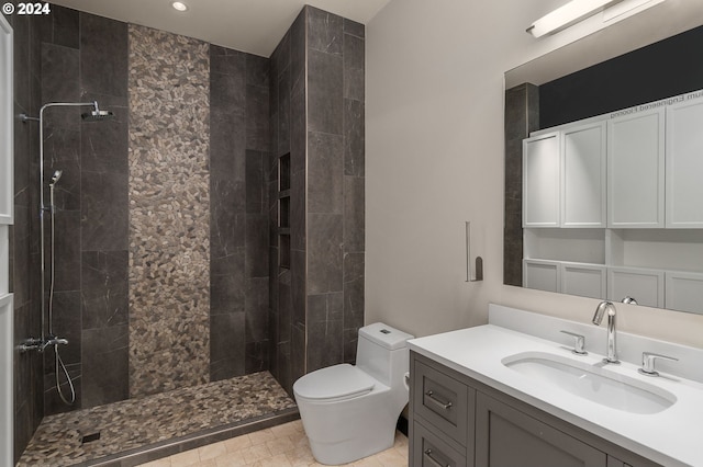 bathroom with a tile shower, vanity, and toilet