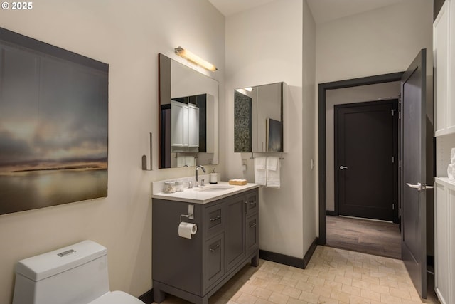 bathroom featuring toilet, baseboards, and vanity