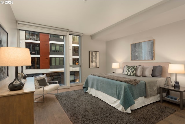 bedroom with access to exterior, a wall of windows, and wood finished floors