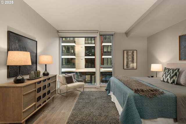 bedroom with expansive windows, access to outside, and wood finished floors