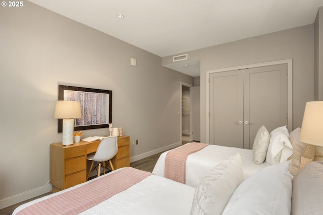 bedroom with a closet, visible vents, baseboards, and wood finished floors