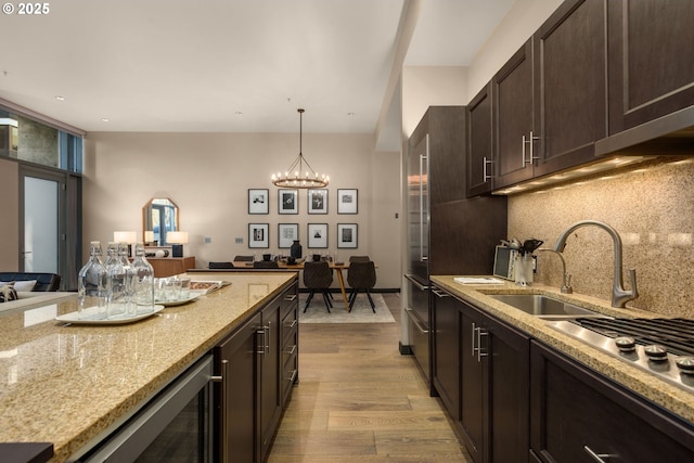 kitchen featuring backsplash, an inviting chandelier, dark brown cabinets, wood finished floors, and beverage cooler