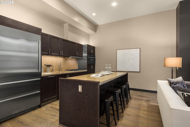 kitchen featuring tasteful backsplash, a breakfast bar area, a center island, stainless steel appliances, and light wood-type flooring