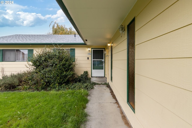 view of exterior entry featuring a lawn