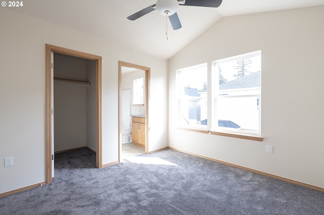 unfurnished bedroom with a closet, a spacious closet, ensuite bathroom, carpet flooring, and ceiling fan