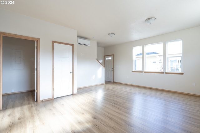 unfurnished living room with an AC wall unit and light hardwood / wood-style flooring