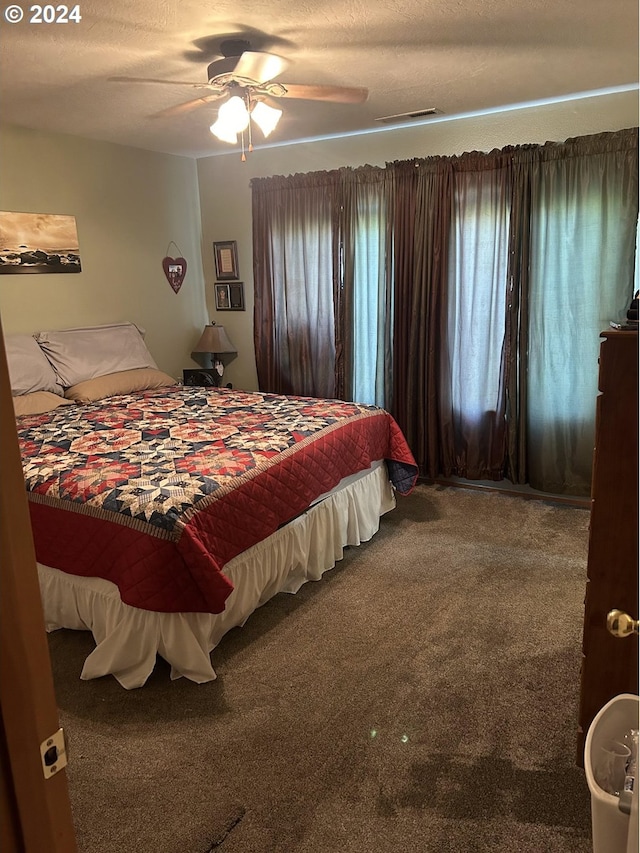 carpeted bedroom featuring a textured ceiling and ceiling fan