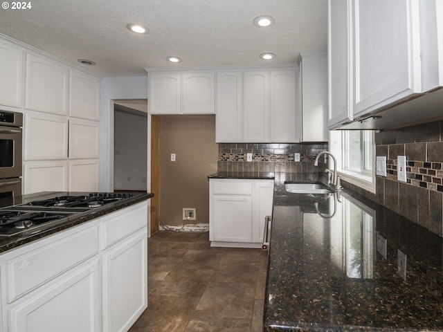 kitchen featuring dark stone countertops, sink, white cabinets, and a textured ceiling