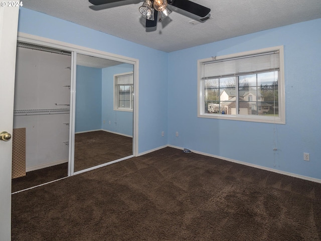 unfurnished bedroom with ceiling fan, a closet, dark carpet, and a textured ceiling