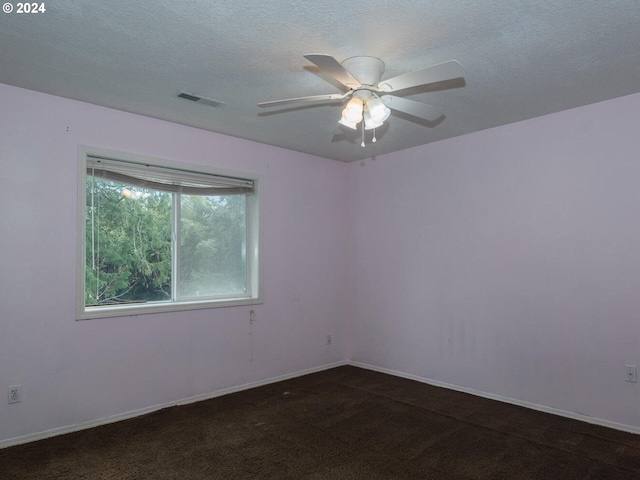 spare room with ceiling fan, dark carpet, and a textured ceiling