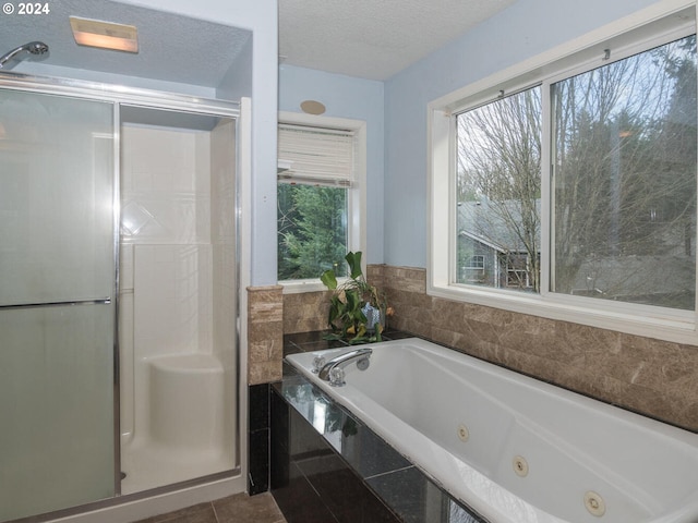 bathroom with plus walk in shower, a textured ceiling, and tile patterned flooring