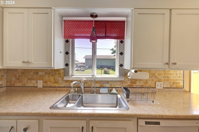 kitchen with pendant lighting, backsplash, white dishwasher, sink, and white cabinets