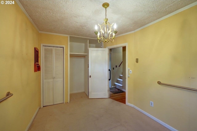 unfurnished bedroom with ornamental molding, a textured ceiling, a notable chandelier, and carpet floors