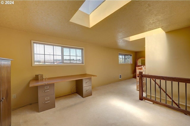 carpeted office featuring a skylight, a textured ceiling, and a healthy amount of sunlight