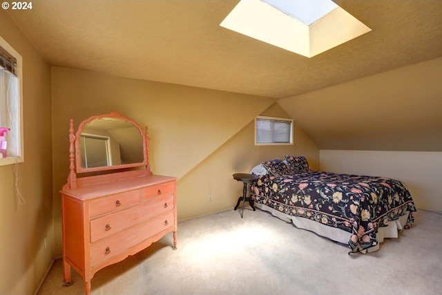 carpeted bedroom featuring multiple windows, vaulted ceiling with skylight, and a textured ceiling