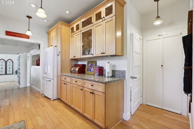 kitchen with white fridge, light hardwood / wood-style flooring, decorative light fixtures, light stone counters, and light brown cabinets