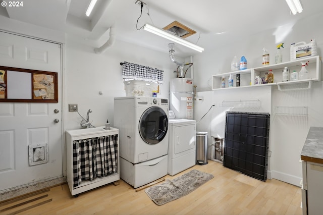 clothes washing area with light wood-type flooring, water heater, and washer and dryer