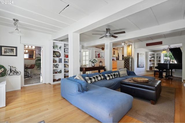 living room featuring built in shelves, ceiling fan, beam ceiling, and wood-type flooring