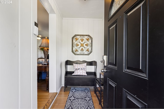 entryway featuring wood walls, light hardwood / wood-style floors, and crown molding