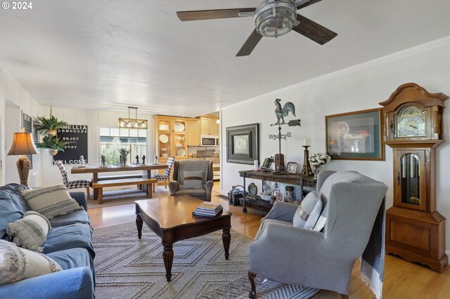 living room featuring crown molding, hardwood / wood-style flooring, and ceiling fan