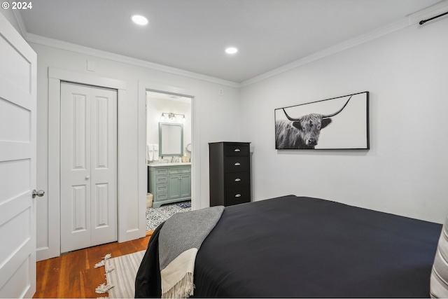 bedroom featuring dark wood-type flooring, ensuite bath, ornamental molding, and a closet