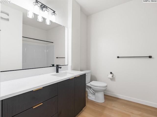 bathroom featuring hardwood / wood-style floors, vanity, toilet, and walk in shower