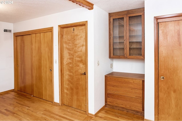 hall with a textured ceiling and light wood-type flooring