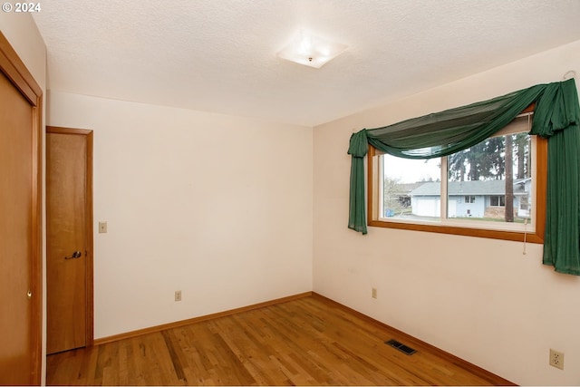 unfurnished bedroom with a closet, a textured ceiling, and hardwood / wood-style flooring