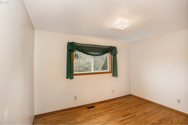 unfurnished room featuring wood-type flooring and a textured ceiling