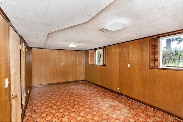 basement featuring a textured ceiling and wood walls