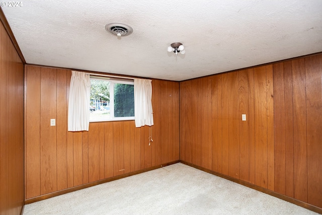 carpeted spare room featuring a textured ceiling and wooden walls