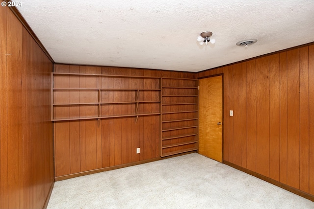 carpeted empty room with wooden walls and a textured ceiling