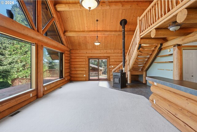 unfurnished living room with a wood stove, log walls, light colored carpet, and wooden ceiling