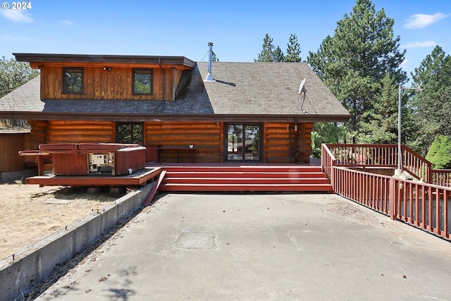 back of house featuring a hot tub, log siding, and a shingled roof