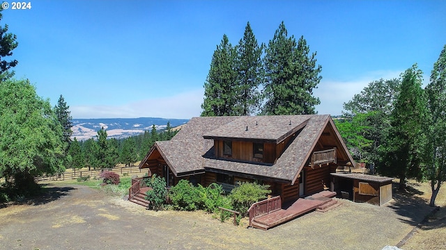 view of front facade with a mountain view, log exterior, and fence