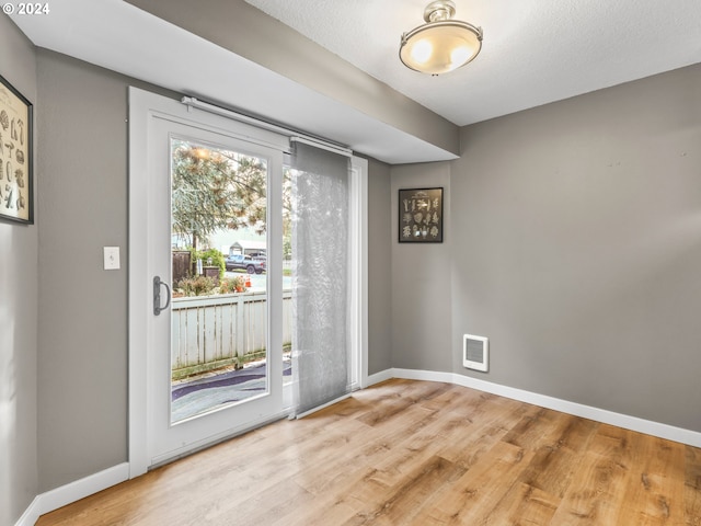 doorway to outside featuring a textured ceiling and light wood-type flooring