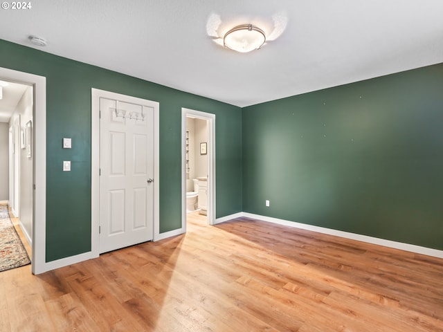 unfurnished bedroom with connected bathroom, light hardwood / wood-style flooring, and a closet