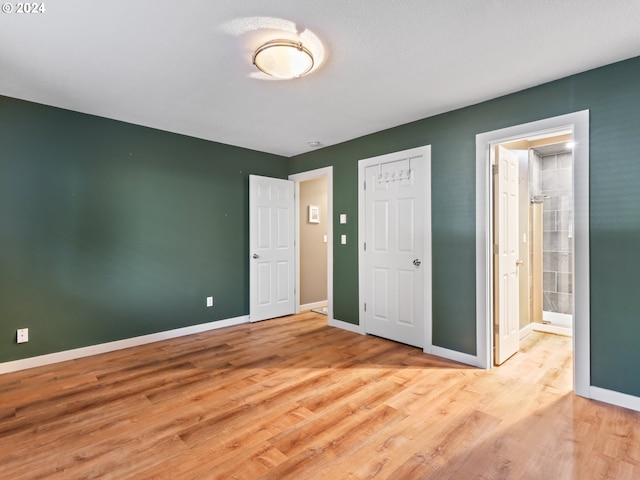 unfurnished bedroom featuring light wood-type flooring and ensuite bathroom