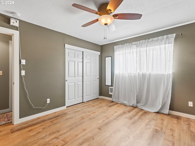 unfurnished bedroom with a textured ceiling, light wood-type flooring, a closet, and ceiling fan