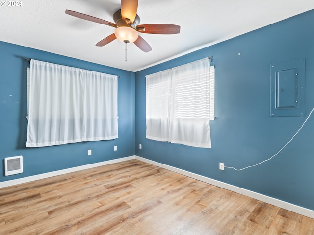 unfurnished room with hardwood / wood-style floors, electric panel, and ceiling fan