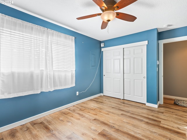 unfurnished bedroom featuring a textured ceiling, light hardwood / wood-style flooring, a closet, and ceiling fan