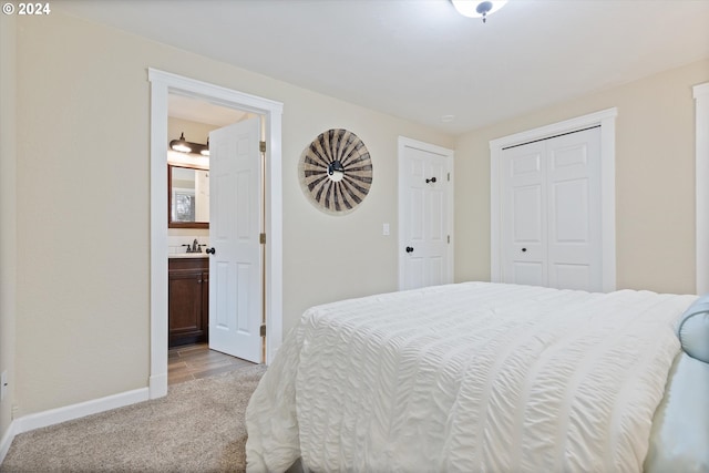 bedroom with ensuite bathroom, light colored carpet, and sink