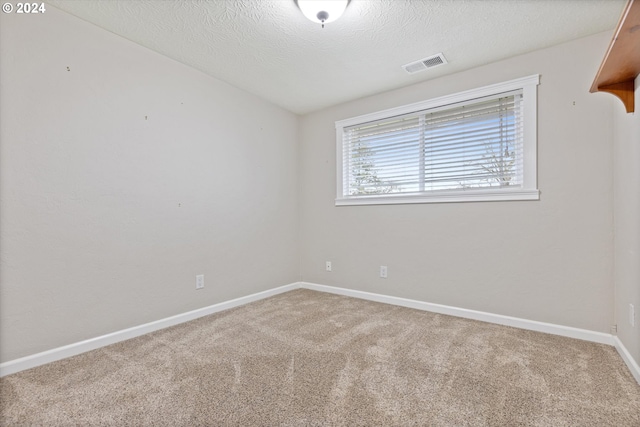 carpeted empty room with a textured ceiling