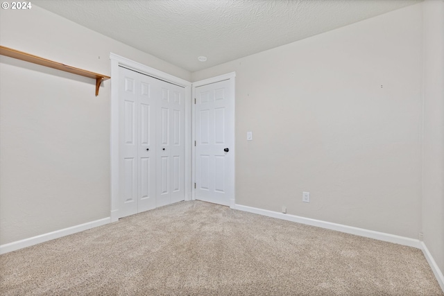 unfurnished bedroom with a textured ceiling, carpet floors, and a closet