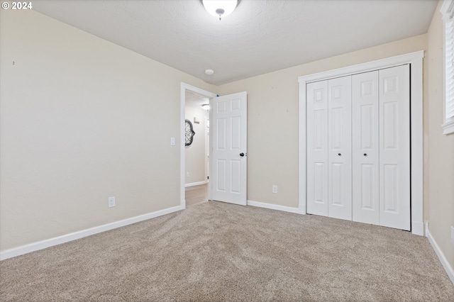 unfurnished bedroom with carpet flooring, a textured ceiling, and a closet