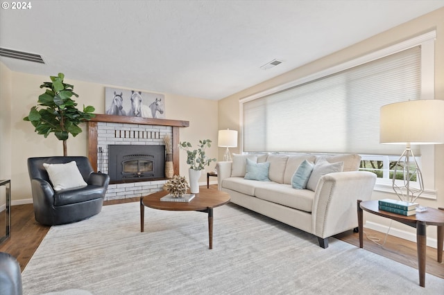 living room featuring wood-type flooring and a brick fireplace