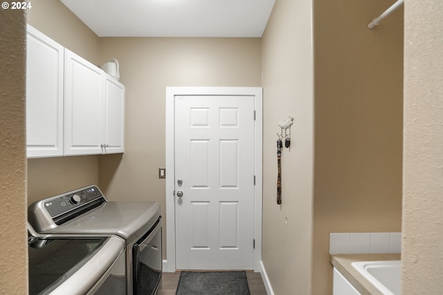 laundry area with hardwood / wood-style floors, washer and clothes dryer, and cabinets