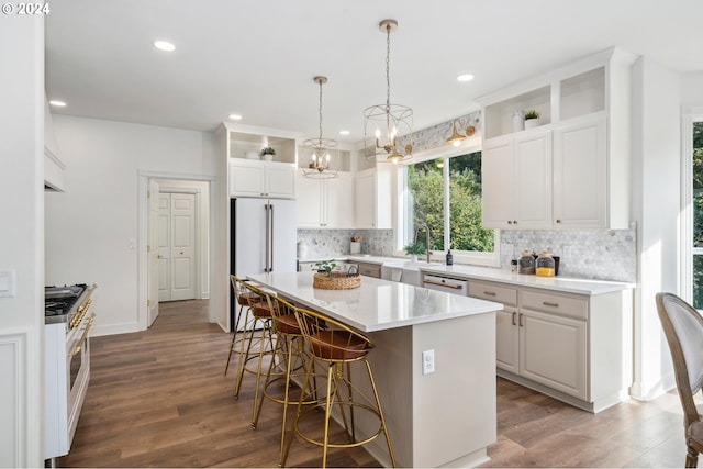 kitchen featuring a kitchen island, an inviting chandelier, dark wood-type flooring, white cabinetry, and premium appliances